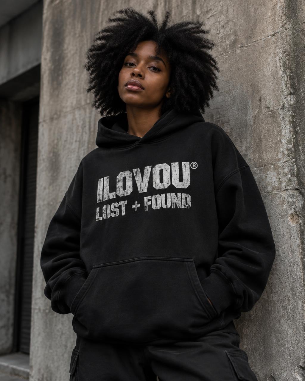 Woman wearing the black Found Era hoodie against a concrete wall